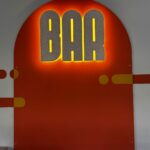Enseigne lumineuse BAR en matériau coquillages recyclés sur arche orange, signalétique intérieure du Laps à Nantes